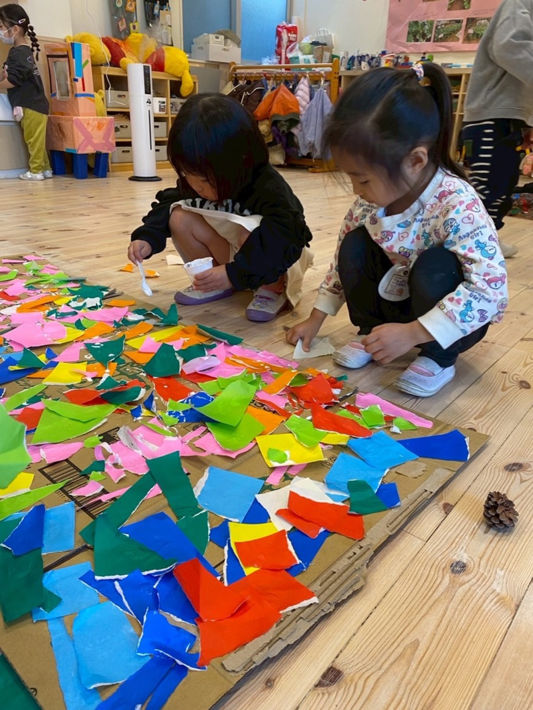 色紙を貼って共同制作を楽しむ子どもたち